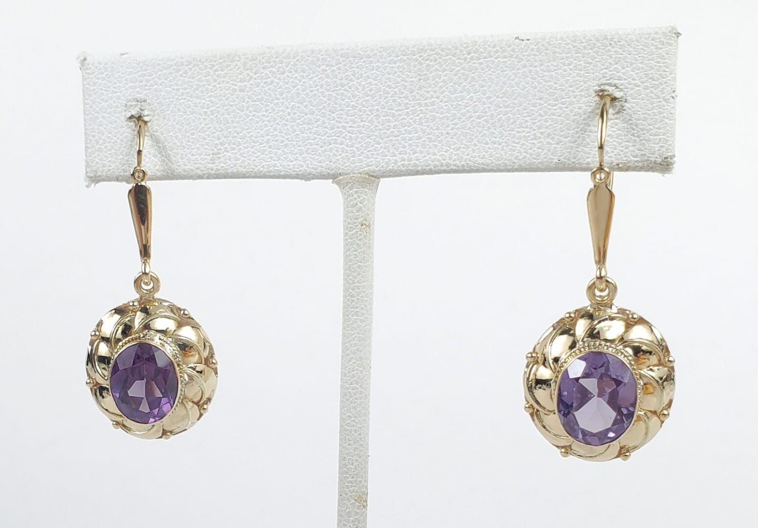 Gold earrings with purple gemstones displayed.