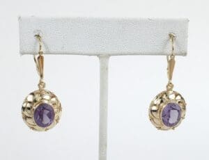 Gold earrings with purple gemstones displayed.