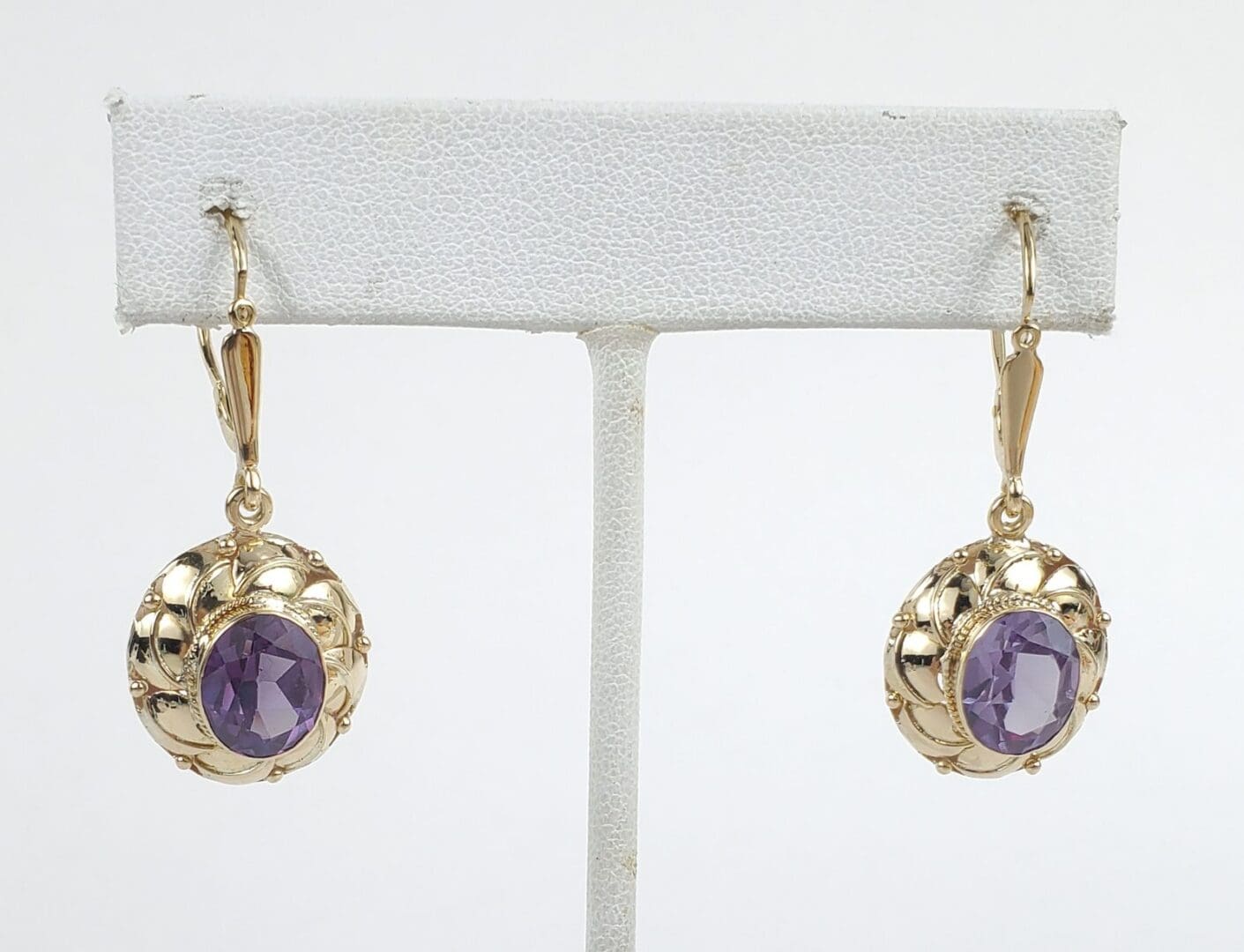 Gold earrings with purple gemstones displayed.