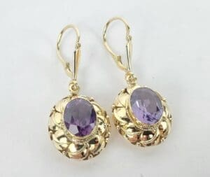 Gold earrings with purple gemstones.