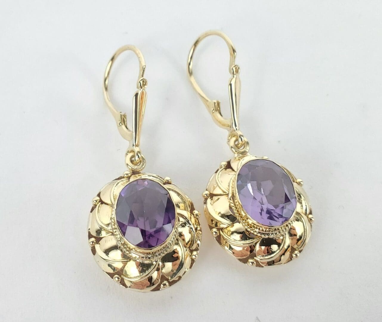Gold earrings with purple gemstones.