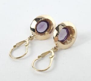 Gold earrings with purple gemstones.