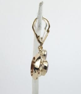 Gold spaceship charm on earring hoop.
