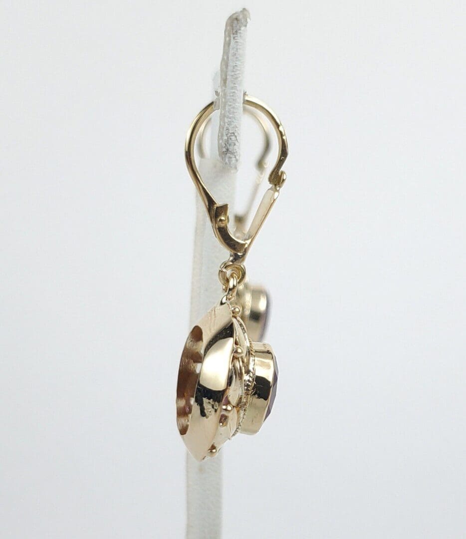 Gold spaceship charm on earring hoop.