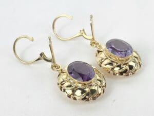 Gold earrings with purple gemstones.
