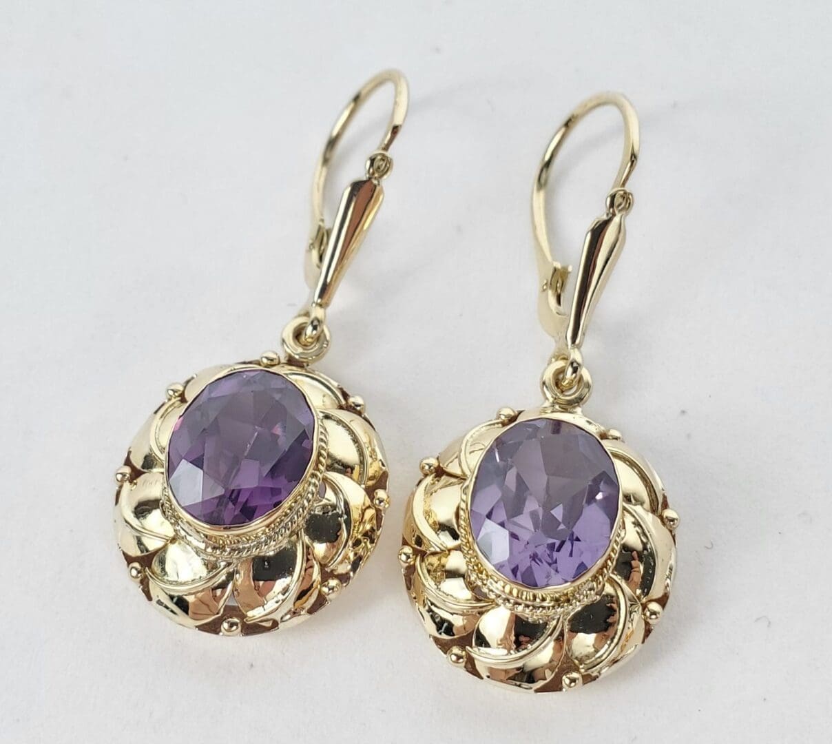 Gold earrings with purple gemstones.