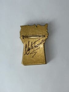 Gold pin with signature on the back.