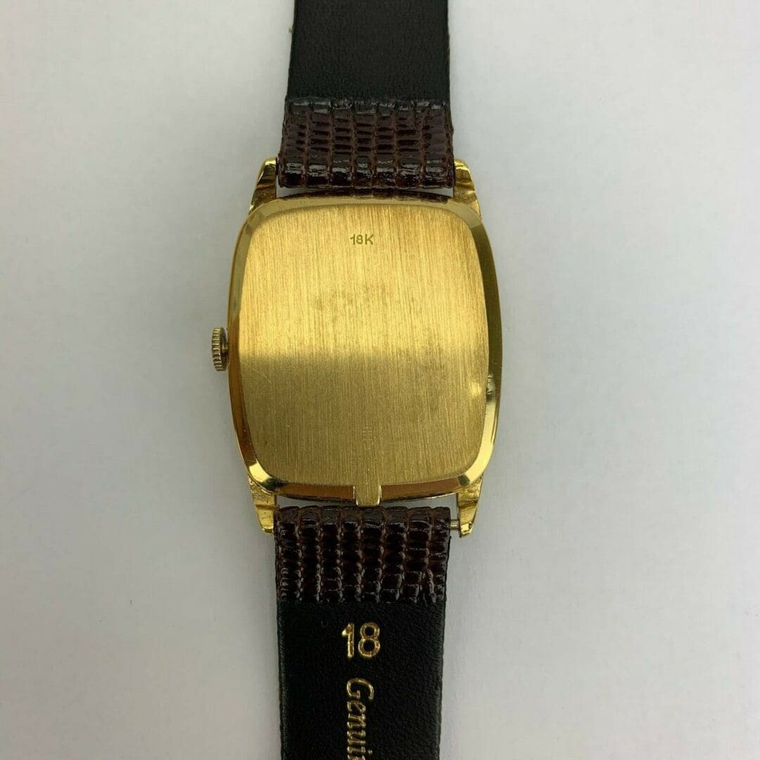 Gold watch back with black leather strap.