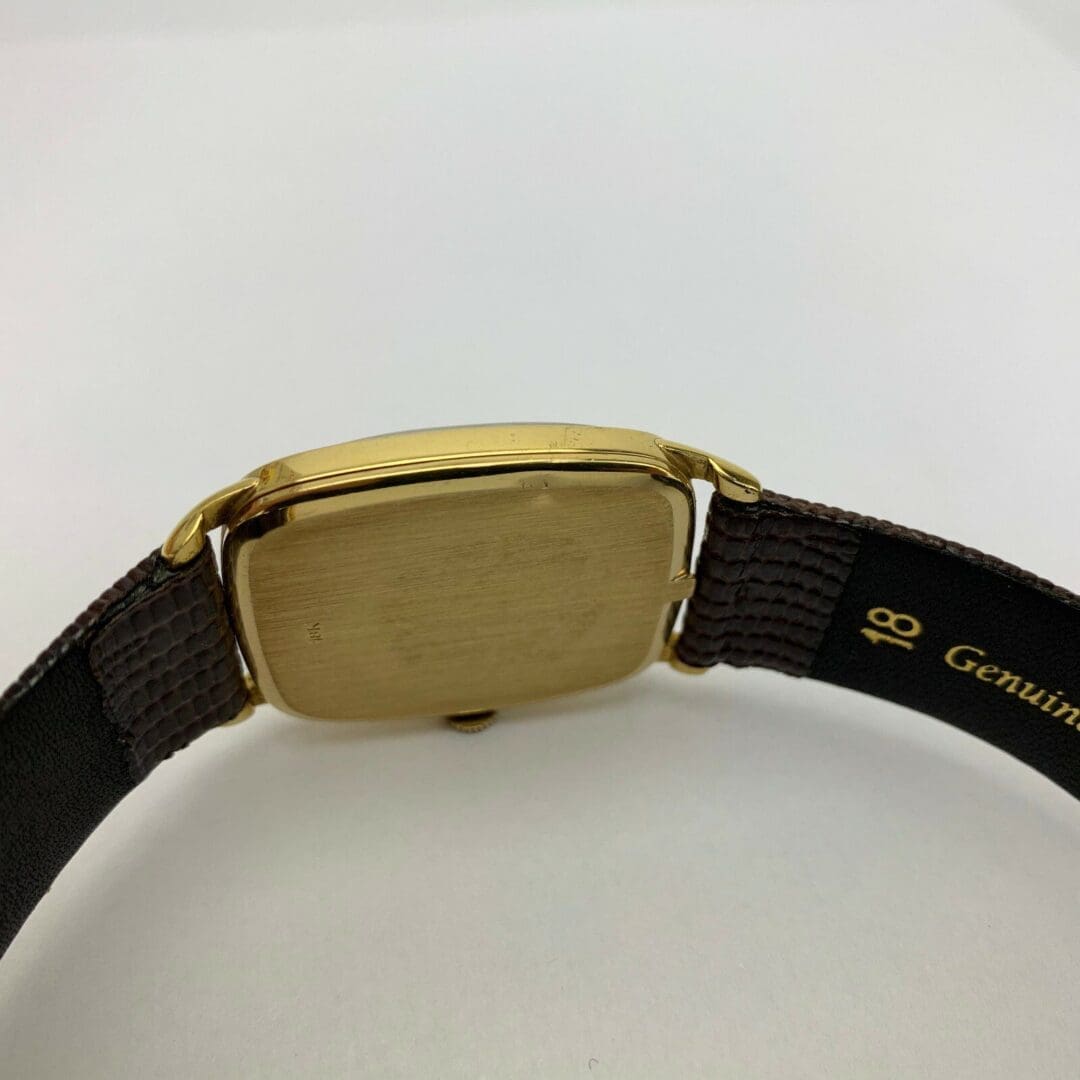 Gold watch with brown leather strap.
