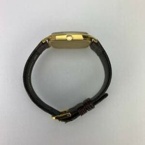 Gold watch with dark leather strap.