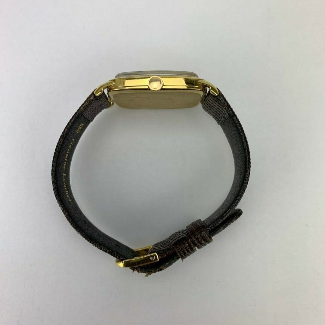 Gold watch with dark leather strap.