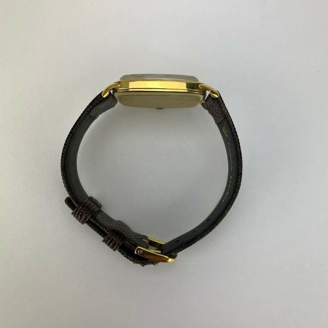 Gold watch with brown leather strap.