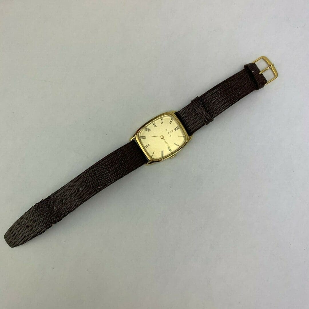 Gold wristwatch with brown leather strap.