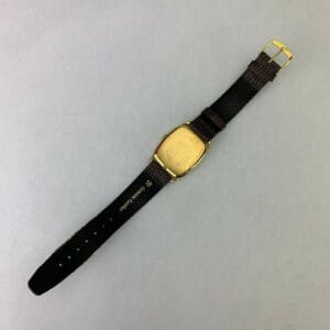 Gold watch with black leather strap.