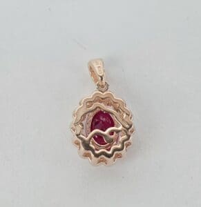 Gold pendant with red gemstone centerpiece.