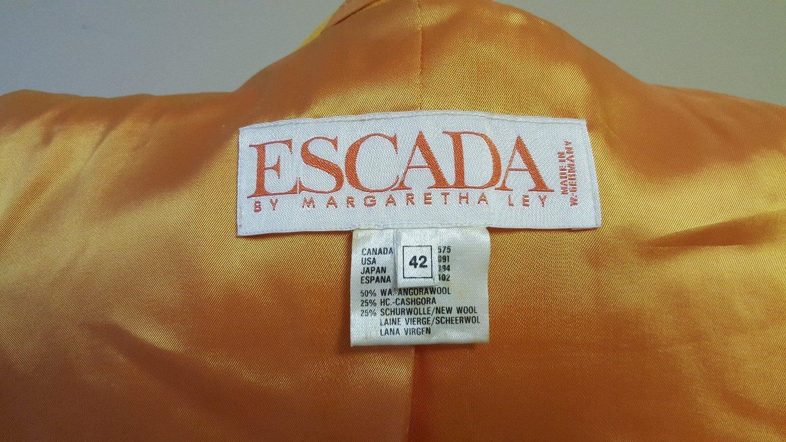 Escada clothing label on orange fabric background.