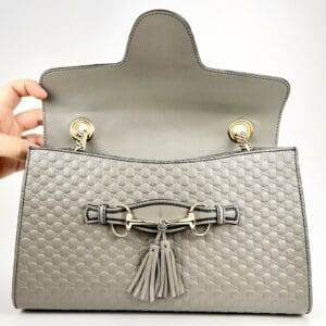 Gray handbag with open flap and tassels.
