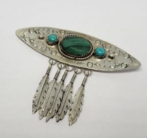 Silver brooch with feathers and turquoise stones.