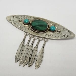 Silver brooch with feathers and turquoise stones.