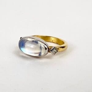 Gold ring with oval moonstone and diamond.