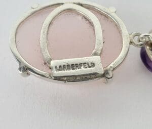 Silver pendant with pink stone and engraving.