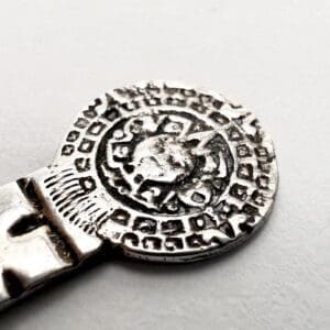 Silver metal object with intricate circular design.