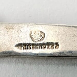 Silver object with engraved hallmark and text.