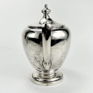 Silver sugar bowl with ornate lid.