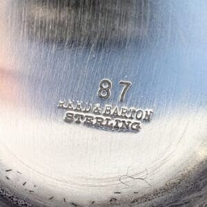 Silver object with engraved text and numbers.
