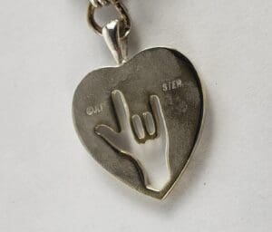 Heart pendant with hand sign cutout.