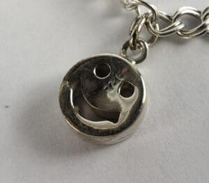 Silver smiley face charm on chain.