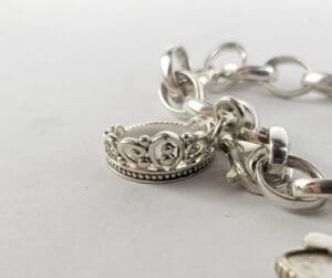 Silver crown charm on a bracelet chain.