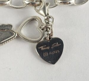 Heart-shaped silver charm with engraved text.
