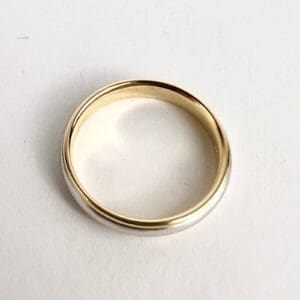 Gold wedding band on white background.