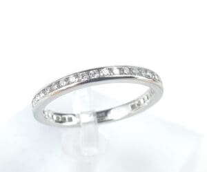 Diamond-studded silver ring on display stand.