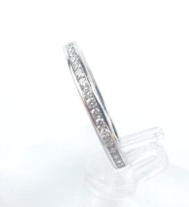 Diamond-studded silver ring on clear stand.