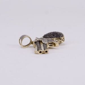 Gold gun-shaped pendant with black stones.