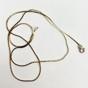 Gold chain necklace with clasp on white.