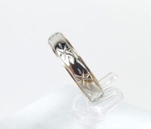 Silver ring with star engravings displayed upright.