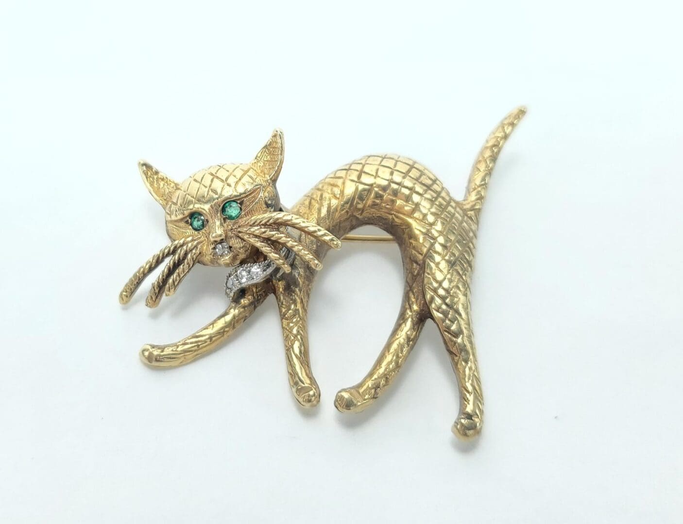Golden cat brooch with emerald eyes.