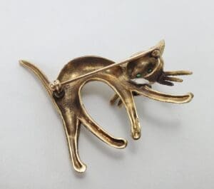 Gold cat brooch with green eyes.