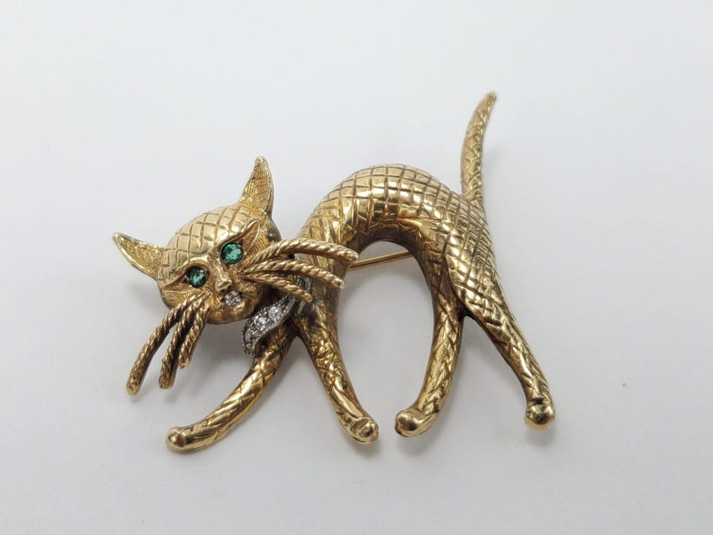 Gold cat brooch with green eyes.