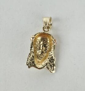Gold pendant with a detailed face engraving.