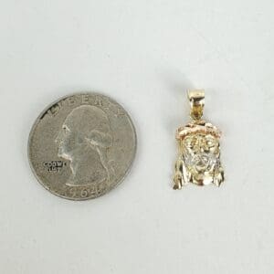 Coin beside small Jesus face pendant.