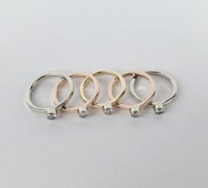 Five diamond rings in different metal tones.
