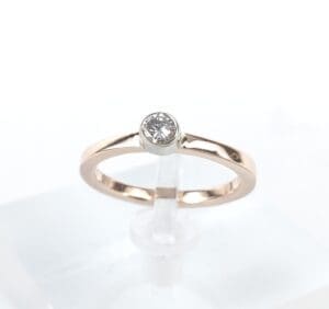 Gold ring with single diamond on stand.