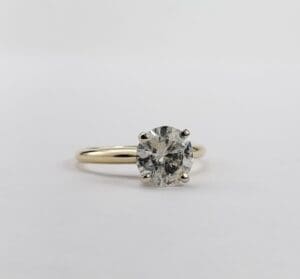 Diamond solitaire ring on white background.