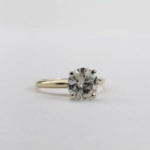 Diamond solitaire ring on white background.
