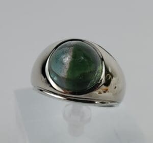Silver ring with green gemstone on display.