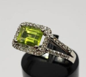 Silver ring with green gemstone and diamonds.